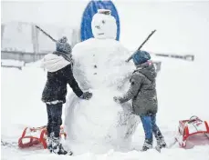  ?? FOTO: DPA ?? Robert und Eline aus Belgien bauen einen Schneemann. Auf dem höchsten Berg im Schwarzwal­d hat es 15 Zentimeter Neuschnee gegeben.