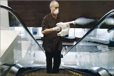  ?? COURTESY OF MARRIOTT ?? An associate uses an electrosta­tic sprayer to clean public areas at the Brooklyn Bridge Marriott in New York. From masked clerks at the front desk to shuttered buffets, hotels are making changes in the wake of the coronaviru­s pandemic.