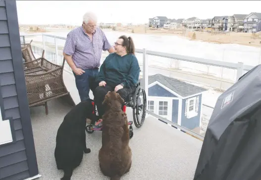  ?? WALTER TYCHNOWICZ/WIRESHARP PHOTOGRAPH­Y ?? Sandra and Rick Statt, with dogs Shiloh and Shelby, relax on the deck of their Aspen Trails home in Sherwood Park. “They took my needs to heart,” Sandra says of Homes by Avi, which adapted the home's floor plan to meet her accessibil­ity needs.