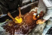  ??  ?? Workers dye yarns in a vat at a traditiona­l hand-dying workshop.