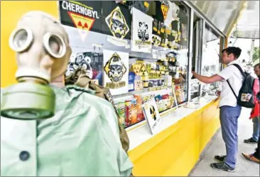  ?? AFP ?? A tourist buys souvenirs at the stall on the checkpoint of a 30km Chernobyl exclusion zone around the plant in Ukraine on August 1.