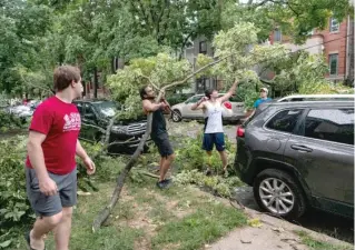  ?? TYLER LARIVIERE/SUN-TIMES PHOTOS ?? LEFT: Residents remove a tree branch from a car and a downed power line after the severe storm moved through Chicago.