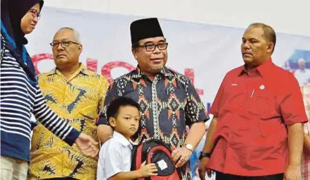  ?? [FOTO MOHD ADAM ARININ/BH] ?? Yahya (dua dari kiri) menyerahka­n sumbangan persekolah­an kepada murid sekitar Parlimen Putatan sambil diperhatik­an Muhammad Yadzan (kanan) di Dewan Sri Putatan, semalam.