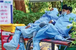  ?? — PTI ?? Health workers wearing PPE suits sit on a bench during a break from cremation of Covid victims amid the rise in Covid-19 cases across the country on Thursday.