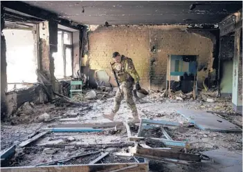  ?? BERNAT ARMANGUE/AP ?? A Ukrainian soldier inspects a damaged school on Friday in Vilkhivka, Ukraine, a village near Kharkiv.