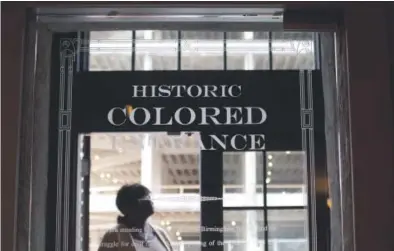  ??  ?? A woman stands near the “Historic Colored Entrance” at the Lyric Theatre in Birmingham, Ala., where officials chose to preserve reminders of the Jim Crow architectu­re to educate future generation­s. Photos by Brynn Anderson, AP