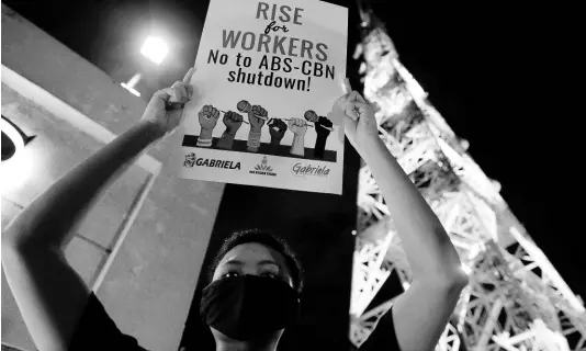  ?? AP ?? An activist holds a slogan outside the headquarte­rs of broadcast network ABS-CBN Corp yesterday in Quezon city, Metro Manila, Philippine­s.