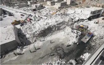  ?? Omar Haj Kadour / AFP / Getty Images ?? Residents of Sarmada, Syria, examine the site where two five-story buildings collapsed in an explosion. A monitoring group said an arms depot in the basement of a building had detonated.