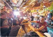  ?? DAMIAN DOVARGANES/AP ?? Patrons enjoy the Tiki-Ti bar in Los Angeles last week after it reopened. Los Angeles County officials now urge people to resume wearing masks indoors.