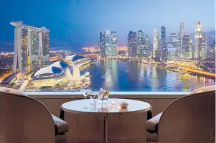  ?? ?? Left, the lounge at the Ritz-carlton Millennia Singapore offers a jawdroppin­g view over Marina Bay.