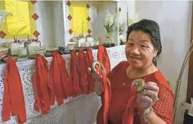  ?? GIOVANNA DELL’ORTO/AP ?? Mee Vang Yang holds her father’s ring-shaped shaman bells Nov. 17 in front of the altar in her living room in St. Paul, Minn.