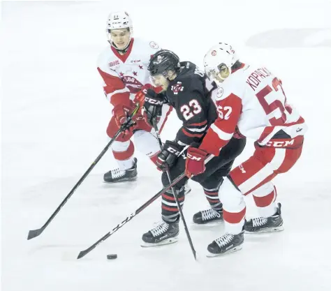  ?? JULIE JOCSAK/ STANDARD STAFF ?? Johnny Corneil of the Niagara IceDogs tries to get the puck through, left, Mac Hollowell and Jack Kopacka of the Sault. Ste. Marie Greyhounds in OHL action at the Meridian Centre in St. Catharines on Thursday,