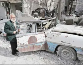  ?? JOSEPH EID/AFP ?? Mohammad Mohiedine Anis inpects his 1957 Mercury Montclair outside his home in Aleppo on March 9.