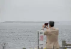  ??  ?? File photo shows tourist taking pictures of an islet making up part of the Habomai Islands at Cape Nosappu, a point on the Nemuro peninsula, Hokkaido prefecture.