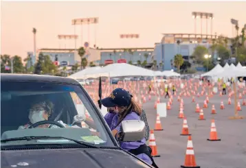  ?? PHILIP CHEUNG/THE NEW YORK TIMES ?? Maria Rivera gets a COVID-19 vaccine injection Thursday at Dodger Stadium. Los Angeles County officials say the call for testing has collapsed. Not long ago, the county was conducting over 350,000 tests weekly.