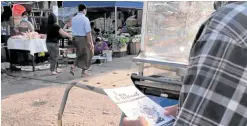  ?? —AFP ?? THE OLD WAY This screengrab from an AFPTV video footage shows a man reading an undergroun­d newsletter distribute­d in a market area in Yangon.