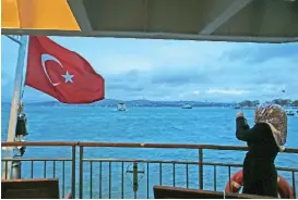  ??  ?? A woman takes pictures on a boat crossing the Bosporus in Istanbul.