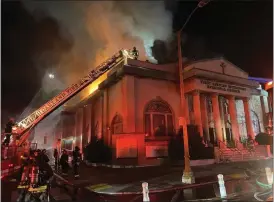  ?? COURTESY OF MICHAEL HUNT — OAKLAND FIRE DEPARTMENT ?? Oakland Fire Department personnel deploy a ladder to battle flames in the upper section of First African Methodist Episcopal Church in Oakland on Sunday night. Officials say that it's not known if anyone was in the church at the time, but no injuries were reported.