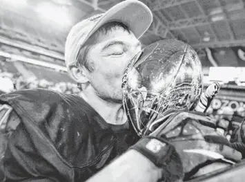  ?? PATRICK BREEN/AZCENTRAL SPORTS ?? Mountain Pointe's Timmy Hernandez gives the Division I championsh­ip trophy a kiss after beating Hamilton at University of Phoenix Stadium on Saturday.