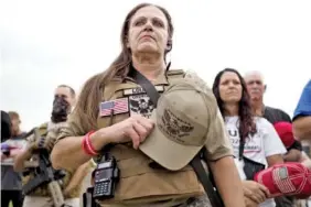  ??  ?? A member of the Georgia III% Martyrs blocks Marjorie Taylor Greene from view as they stand for the national anthem Saturday in Ringgold, Ga.