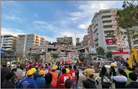  ?? (AP/Ismail Gokmen) ?? Rescue workers try to save people trapped in the debris of a quake-collapsed building Friday in Izmir, Turkey.