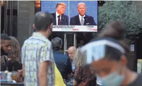  ?? MARIO TAMA/GETTY IMAGES ?? People in West Hollywood, Calif., watch the debate between President Donald Trump and Joe Biden on Sept. 29.