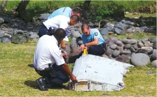  ?? (Prisca Bigot/Zinfos974/Reuters) ?? FRENCH GENDARMES inspect a piece of Boeing 777 debris found on the beach in Saint-Andre, on Reunion Island, on Wednesday.