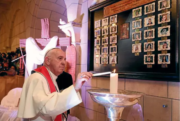  ??  ?? Pope Francis lights a candle at the Coptic St Peter and St Paul’s Church in Cairo, to honour the victims of a suicide bombing there last December which killed 30 people, most of them women.