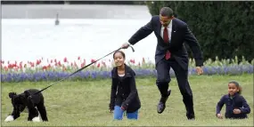  ??  ?? President Barack Obama is almost jerked off his feet as he shows off their new dog Bo, a 6-month-old Portuguese water dog with his daughters Malia, left, and Sasha Obama, right, on the South Lawn of the White House in Washington.
