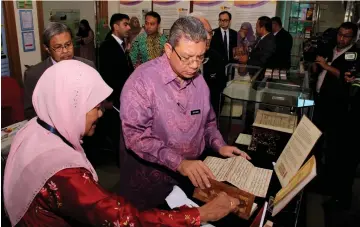  ??  ?? Saifuddin takes a closer look at an old manuscript during his visit to Menara DBP. — Bernama photo