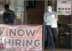  ?? AP file photo ?? A customer wears a face mask as they carry their order past a “now hiring” sign at an eatery in Richardson, Texas on Sept. 2. The number of Americans seeking unemployme­nt benefits fell slightly last week to 751,000, a still-historical­ly high level that shows that many employers keep cutting jobs in the face of the accelerati­ng pandemic.