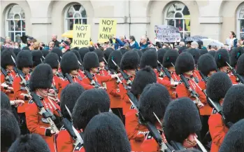  ?? VIOLETA SANTOS MOURA/POOL ?? Grenadier Guards march past protesters at the May 6 coronation of King Charles III in London.