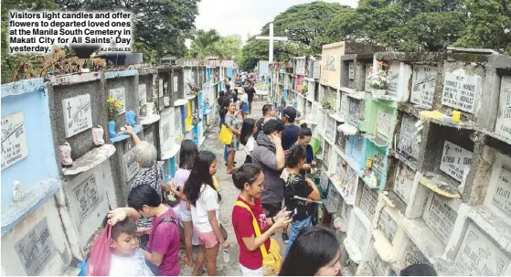  ?? KJ ROSALES ?? Visitors light candles and offer flowers to departed loved ones at the Manila South Cemetery in Makati City for All Saints’ Day yesterday.