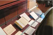  ?? KIN CHEUNG/AP ?? Church archivist Giles Mandelbrot­e looks at a “slave bible,” center, at the exhibition in the Lambeth Palace Library in London. One of the letters in the exhibition was written by an enslaved person in Virginia.
