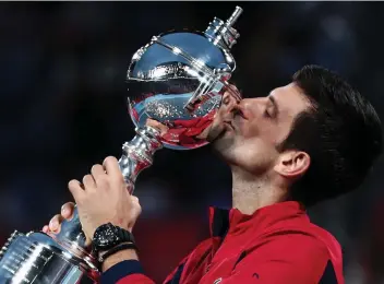  ?? — AFP ?? Serbia’s Novak Djokovic kisses the trophy after winning the men’s singles final against John Millman of Australia at the Japan Open tennis tournament in Tokyo on Sunday.