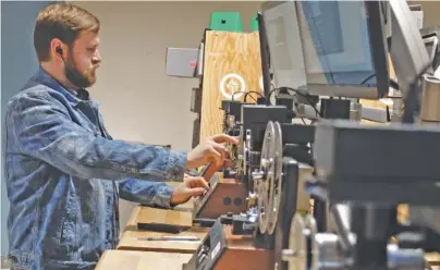  ?? STAFF PHOTOS BY TIM BARBER ?? Kipp Wilkinson spins a reel of film with his finger inside the Legacybox production facility on Holtzclaw Avenue.