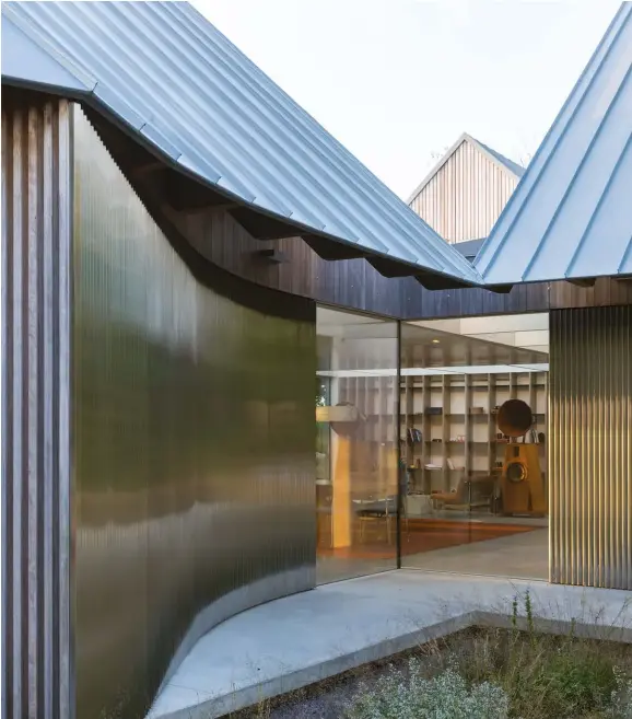  ??  ?? BELOW: In addition to zinc, cladding materials include cedar slats and corrugated steel. The curved area at left houses the entryway.