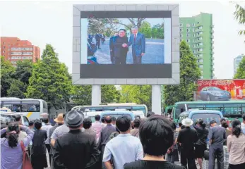  ?? FOTO: DPA ?? Spannung vor dem Gipfel: Passanten am Bahnhof in Pjöngjang betrachten auf einem großen Monitor ein Video mit Nordkoreas Machthaber Kim bei seiner Begrüßung durch Singapurs Premiermin­ister Loong.