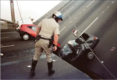  ?? THE ASSOCIATED PRESS ?? A California Highway Patrol officer checks the damage to cars that fell when the upper deck of the Bay Bridge collapsed onto the lower deck during the Loma Prieta earthquake on Oct. 17, 1989.