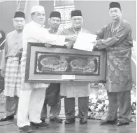  ??  ?? JAMES (kanan) menyampaik­an anugerah Tokoh Maulidur Rasul kepada Haji Sh Kayong sambil diiringi Suhaili Riman (tengah).