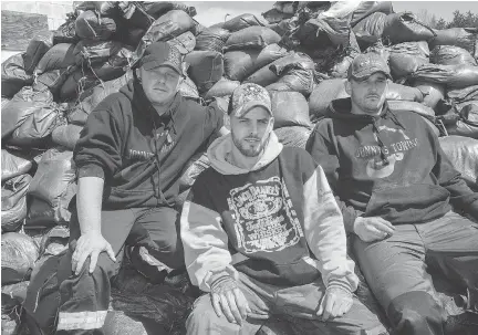  ?? WAYNE CUDDINGTON ?? Rob Ferguson, left, Cory Legue and Jordan Legue have been roving Cumberland’s flooded streets in their Jonny’s Towing flatbed truck delivering sandbags and fuel for generators. The Legues had to seek a dry place to stay themselves.