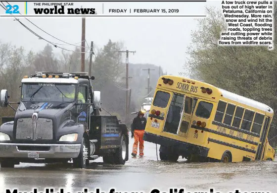  ?? AP ?? A tow truck crew pulls a bus out of high water in Petaluma, California on Wednesday. More rain, snow and wind hit the West Coast, flooding roads, toppling trees and cutting power while raising threats of debris flows from wildfire scars.