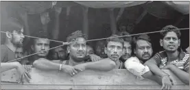  ?? AP-Binsar Bakkara ?? Men from Bangladesh ride in the back of a truck heading to an immigratio­n detention center in Medan, North Sumatra, Indonesia. Officials said a few dozen men were found locked in a house, waiting for a broker to bring them illegally by boat to Malaysia, with some planning to work on palm oil plantation­s.