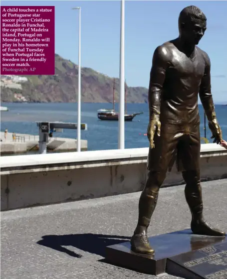  ??  ?? A child touches a statue of Portuguese star soccer player Cristiano Ronaldo in Funchal, the capital of Madeira island, Portugal on Monday. Ronaldo will play in his hometown of Funchal Tuesday when Portugal faces Sweden in a friendly soccer match....