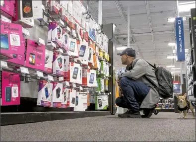  ?? Bloomberg News/DAVID PAUL MORRIS ?? A shopper looks at prepaid cellphones displayed in a Best Buy store in San Francisco in May. The company said Tuesday that its earnings jumped 21 percent in the May to July quarter.