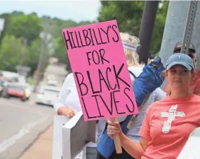  ?? TONY CENTONZE/FOR THE USA TODAY NETWORK ?? A woman holds a sign during an anti-racism rally in Ashland City, Tenn., on June 14. Across the street, another group countered with “All Lives Matter,” while waving American and Confederat­e flags.