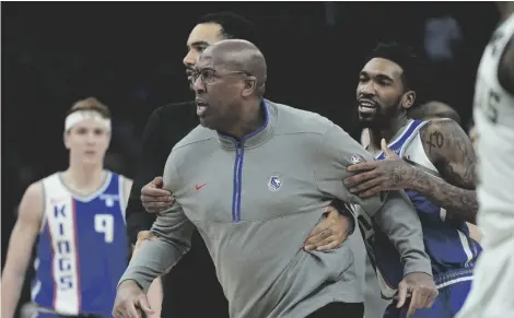  ?? AP PHOTO/MORRY GASH ?? Sacramento Kings head coach Mike Brown is restrained bt Malik Monk as he argues a call during the second half of an NBA basketball game against the Milwaukee Bucks on Sunday in Milwaukee. The Bucks won 143-142 in overtime.