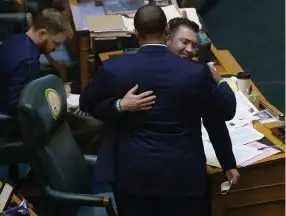  ?? Kathryn Scott, Special to The Denver Post ?? Rep. James Coleman heads over to the desk of House Minority Leader Patrick Neville, right, and gives him a hug on June 12 after Neville announced on the House floor that he will be a “yes“vote on the police reform bill, Senate Bill 217.