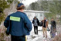  ??  ?? Three men who claimed to be from Sudan and were driven by taxi driver Curtis Seymour, are confronted by Royal Canadian Mounted Police as they prepare to cross illegally the US-Canada border into Hemmingfor­d, Quebec.