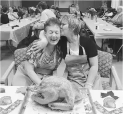  ?? LARRY WONG/ EDMONTON JOURNAL ?? Mona Campbell, left, gets a kiss from Linda Smith at a Thanksgivi­ng dinner that the two friends organized for patients and their families at CapitalCar­e Norwood on Monday. The women’s husbands, Larry Campbell and Ken Smith, are palliative patients there.